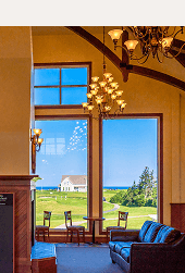 Indoor lounge featuring leather sofas & windows overlooking a golf course and building at Rodd Crowbush Golf & Beach Resort