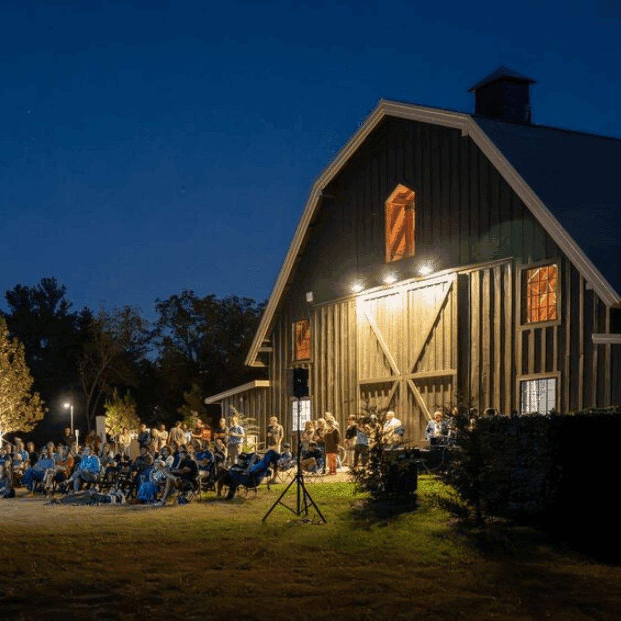 Crowd gathered outside a barn at night for a Rom-Com Movie Night event.