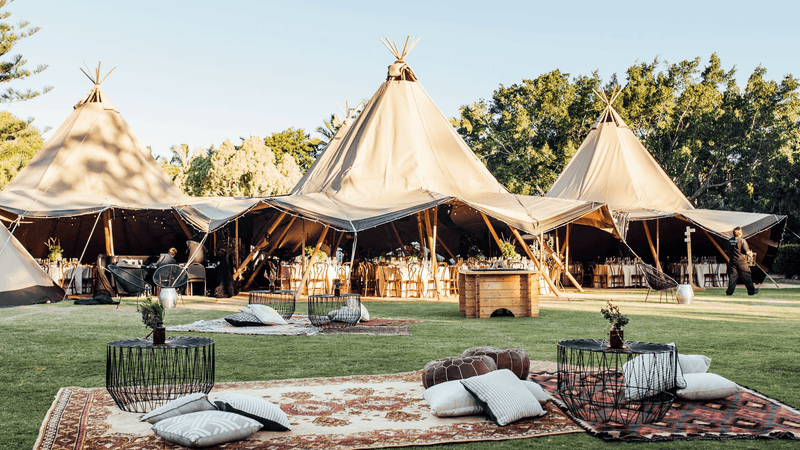 Lawns & beaches with three large tipis with cozy seating amid lush greenery at Novotel Sunshine Coast Resort