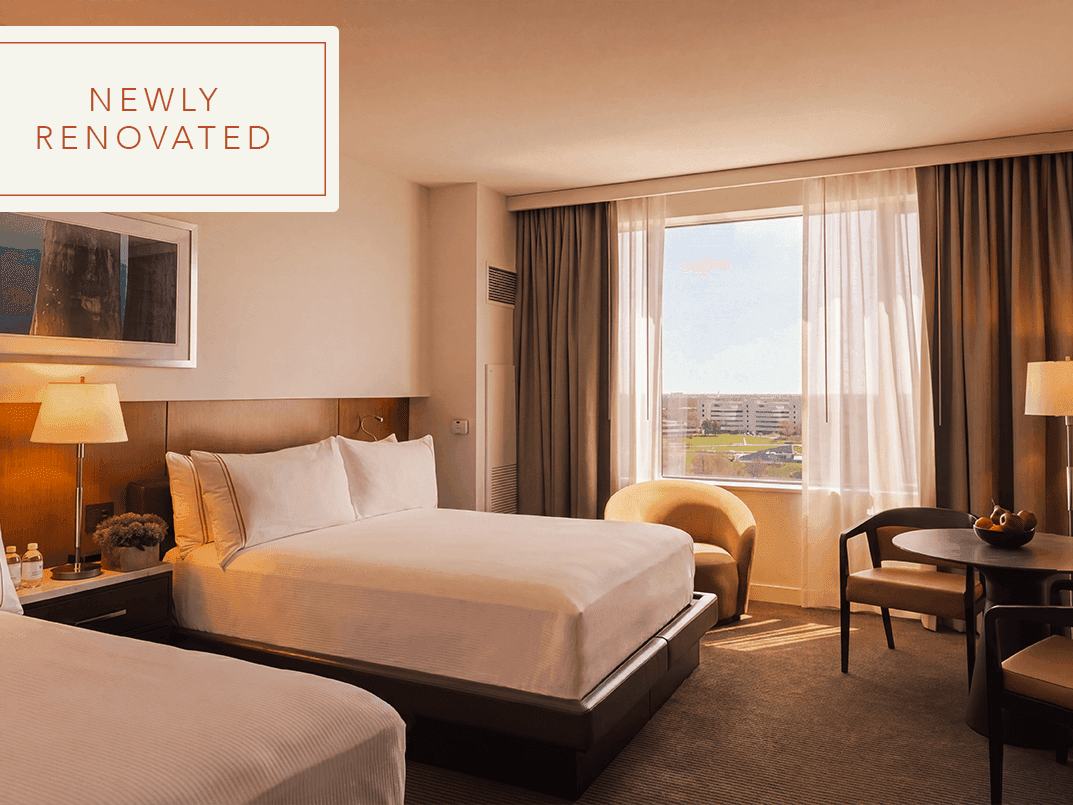 Accessible double queen guestroom with two queen beds, modern furnishings, work desk, and natural light at Hotel Arista.
