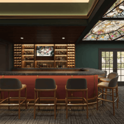 Wooden bar counter with barstools under a stained-glass ceiling panel in the bar at La Tourelle Hotel and Spa