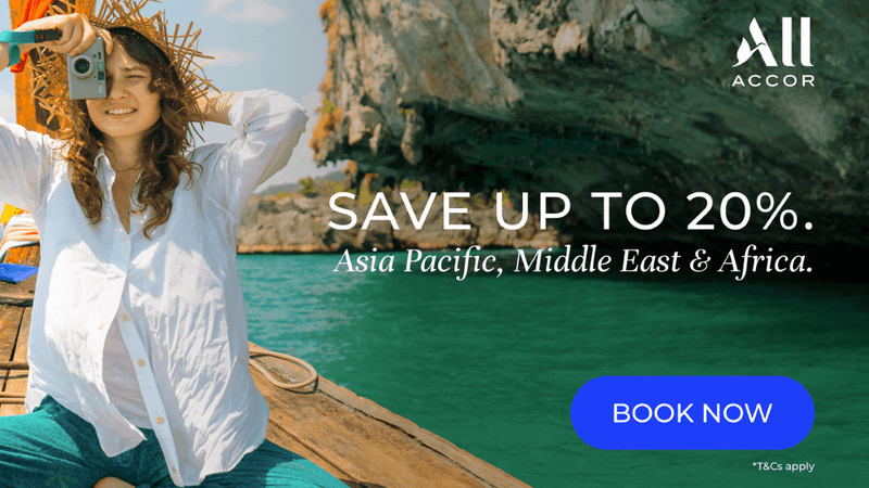 Woman in straw hat holding camera on boat dock with turquoise water and limestone cliffs for ALL ACCOR END OF YEAR SALE.