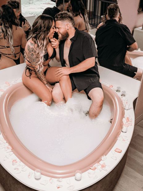 Couple relaxing by the bathtub in Juliette with mirrors at Cove Pocono Resorts