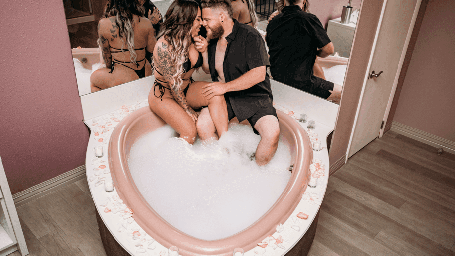 Couple relaxing by the bathtub in Juliette with mirrors at Cove Pocono Resorts