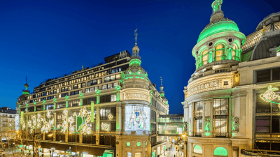 Printemps building facade illuminated with green lighting by street traffic near Hotel Westminster Paris