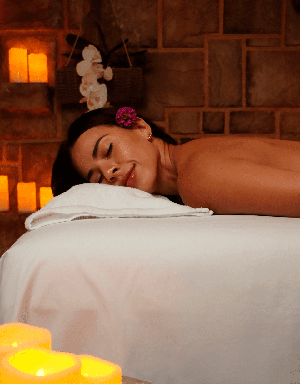 Relaxed woman lies on a spa massage table beside warm candles in Spa Holistic at Playa Los Arcos Beach Resort & Spa