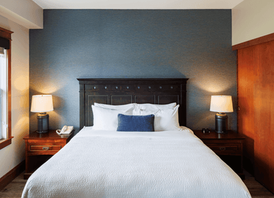Accessible King Suite View with white bed, dark wooden headboard, and blue accent wall at Rodd Crowbush Golf & Beach Resort
