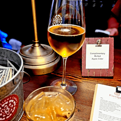 Glass of cider with ice cocktail and small table sign on wooden bar counter at La Tourelle Hotel and Spa