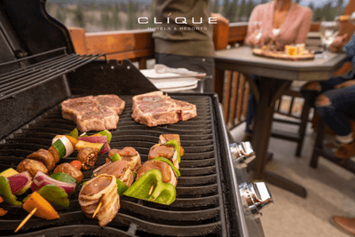 Steaks and vegetable skewers sizzle on a grill on a balcony at Falcon Crest Lodge