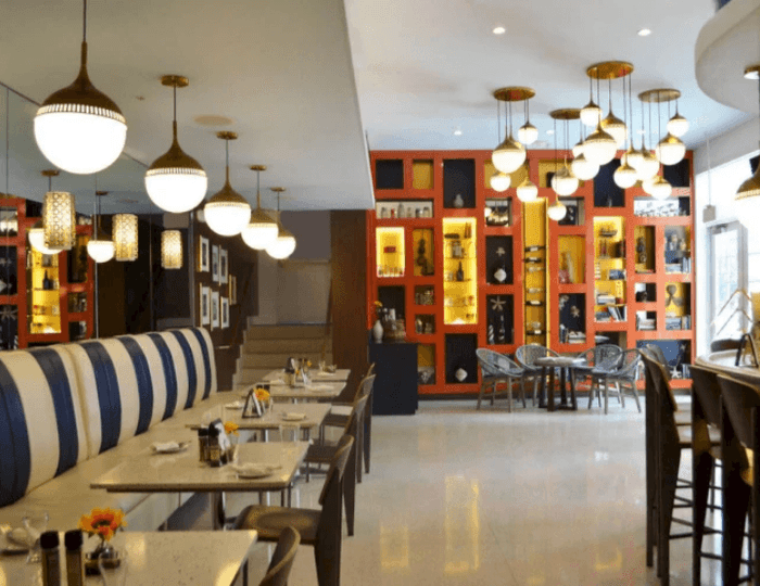 Modern hotel dining area with striped banquette seating, globe pendant lights at Tradewinds Hotel