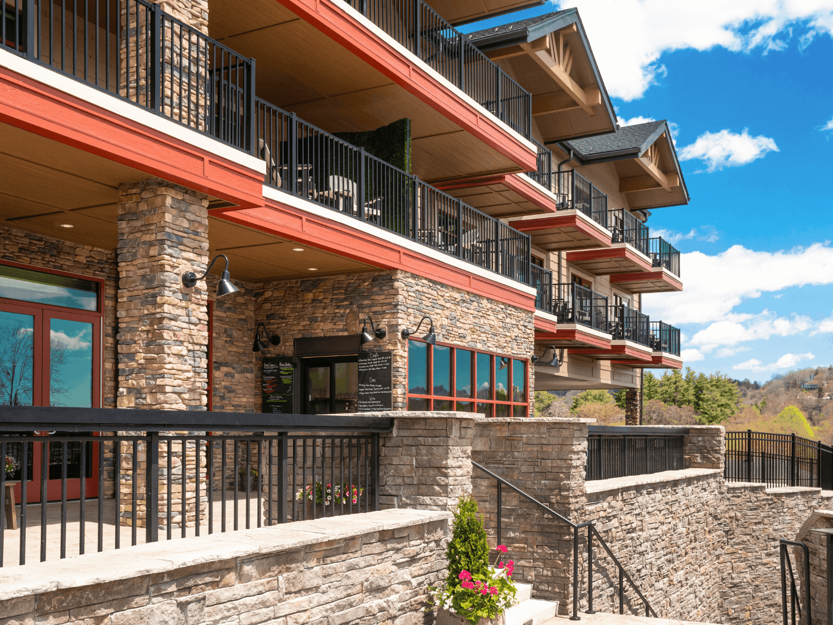 Exterior of the multi-story Embers Hotel with balconies, railings, and a clear blue sky in the background.