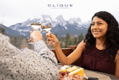 Couple toasts with wine glasses at a table on a wooden balcony at Falcon Crest Lodge