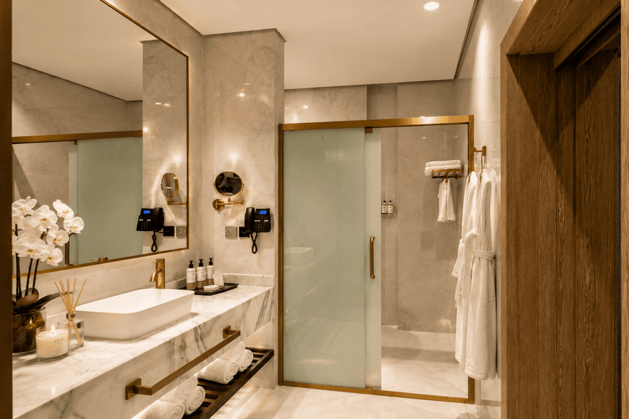 Vanity under mirror beside glass shower in bathroom at Naviti by Warwick Jeddah, capturing stylish hotel rooms in Jeddah