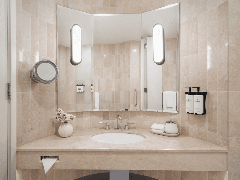 Modern hotel bathroom with marble vanity, round mirrors and minimalist design