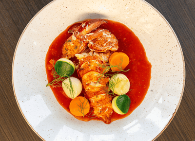Gourmet lobster dish with fresh vegetables in rich red sauce at restaurants in Charlottetown, PEI, in Rodd Hotels & Resorts