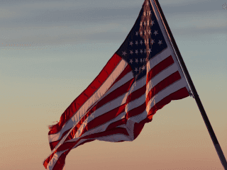 Patriotic display of the American flag billowing in the wind as the sun rises