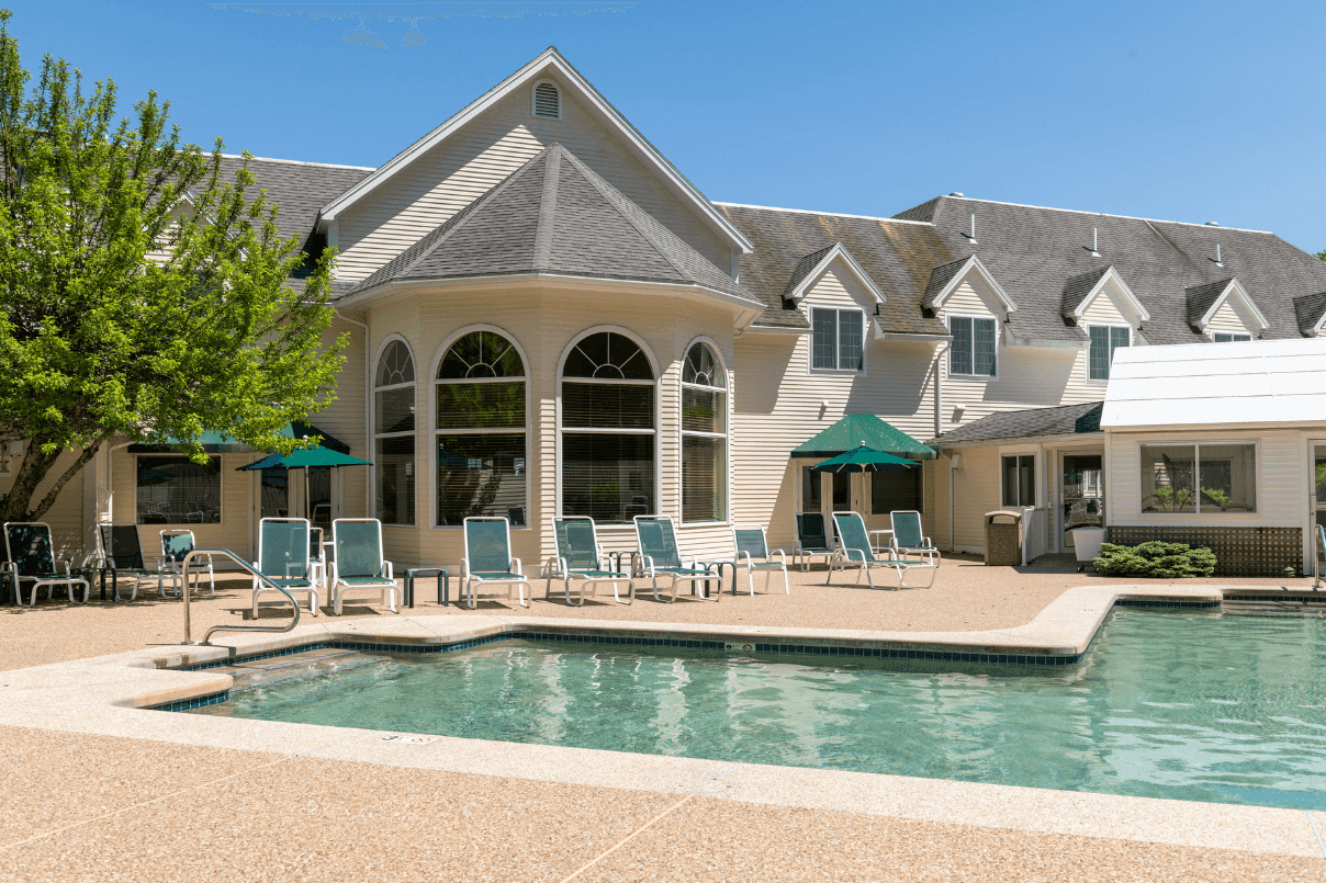 A pool area with lounge chairs and a building in the background.