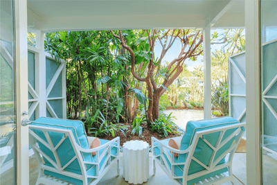 Two white chairs with turquoise cushions on a porch with lush greenery at Catalina Island Company