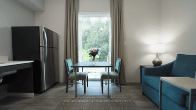Dining table and chairs by a large window with blue sofa beside a floor lamp in a cozy suite at Star Suites Vero Beach