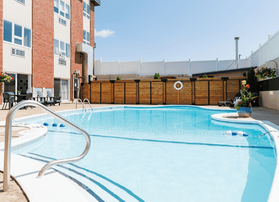 Clear outdoor swimming pool surrounded by modern wood fencing and red brick hotel exterior at Rodd Moncton
