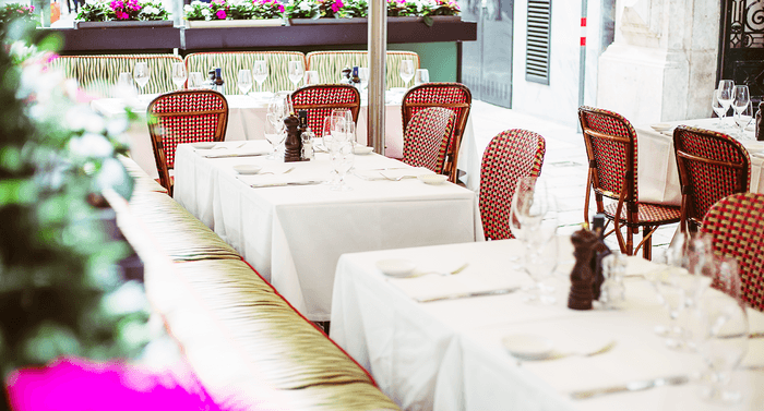 Red chairs on set tables with white tablecloths on the terrace