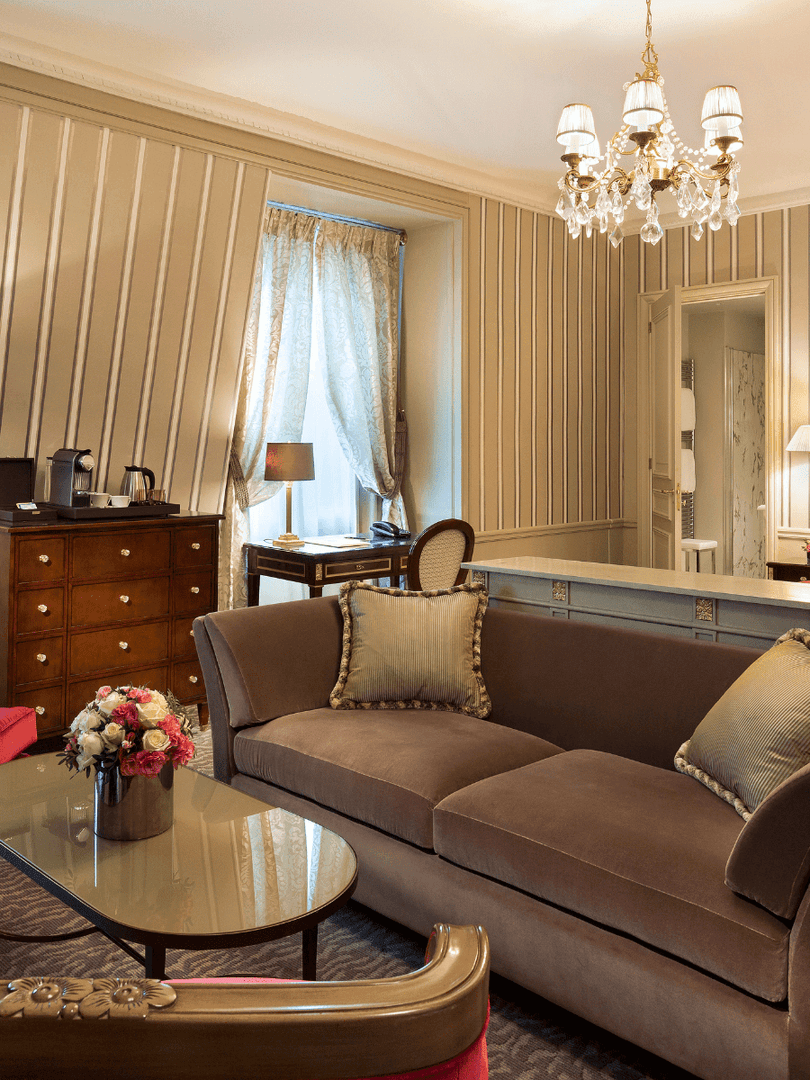 Living area with a plush sofa near bed in Deluxe Suite Parisienne at Hotel Westminster Paris