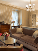 Living area with a plush sofa near bed in Deluxe Suite Parisienne at Hotel Westminster Paris