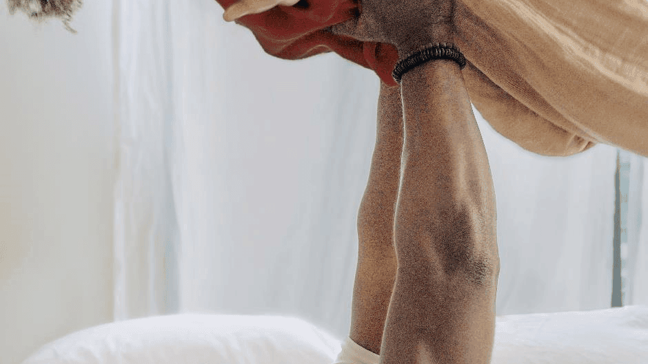 Adult holding a baby upside down playfully over a bed in a bright room at Sofitel Brisbane Central