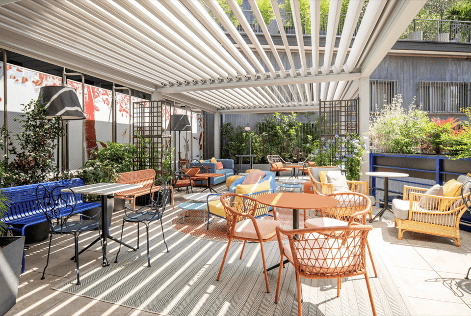 Terrazza moderna con pergolato bianco, arredi colorati e piante per aperitivi pranzi e cene presso Urban Hive Milano