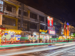 A long-exposure photo of a city street food at night, capturing the vibrant lights and the bustling atmosphere.
