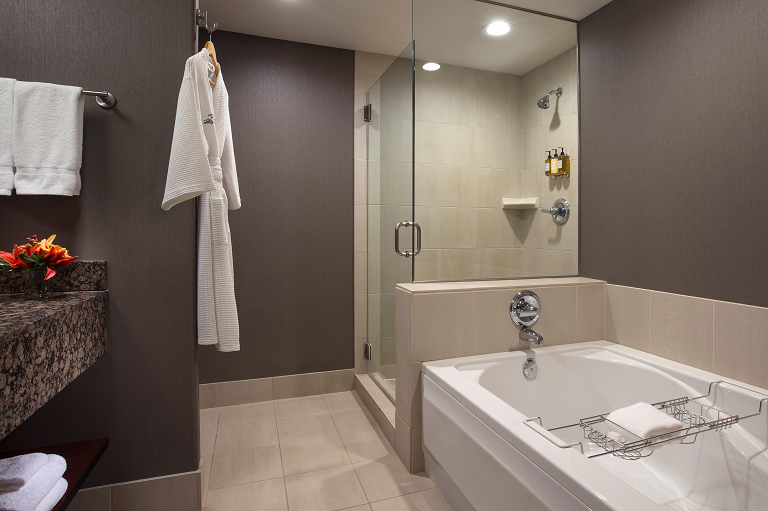 A hotel bathroom with a bathtub, shower, sink, and towels
