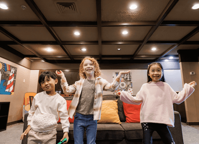 Three smiling children posing in a comfortable lounge area at Rodd Royalty, places to stay in Charlottetown, PEI