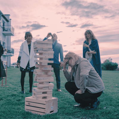 Guests watching a giant wooden block tower game on the lawn during an outdoor event reception at La Tourelle Hotel and Spa