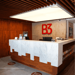 Marble reception counter featuring warm wood paneling under modern ceiling lighting by the lobby of Hotel B3 Virrey