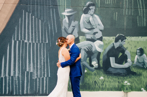 Wedding couple hugging in front of   a mural at Kinship Landing