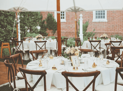 Wedding reception table with floral centerpieces and white tablecloths in a tent at The Exeter Inn