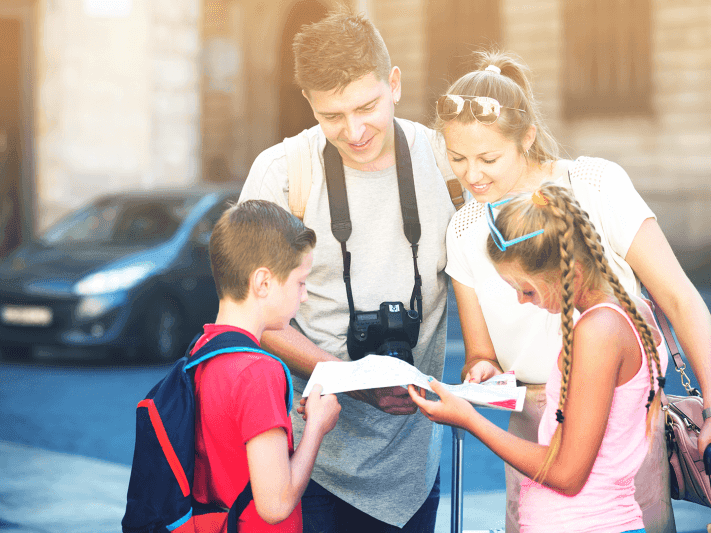 Family looking at the map in the streets on a sunny day near Hotel Grand Chancellor