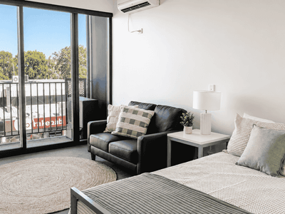 Modern studio apartment with bed, black leather sofa, and balcony access at Student Living - Waymouth
