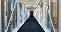 Modern indoor skywalk with floor-to-ceiling glass walls and dark carpeted walkway inside hotel area at Hotel X Toronto