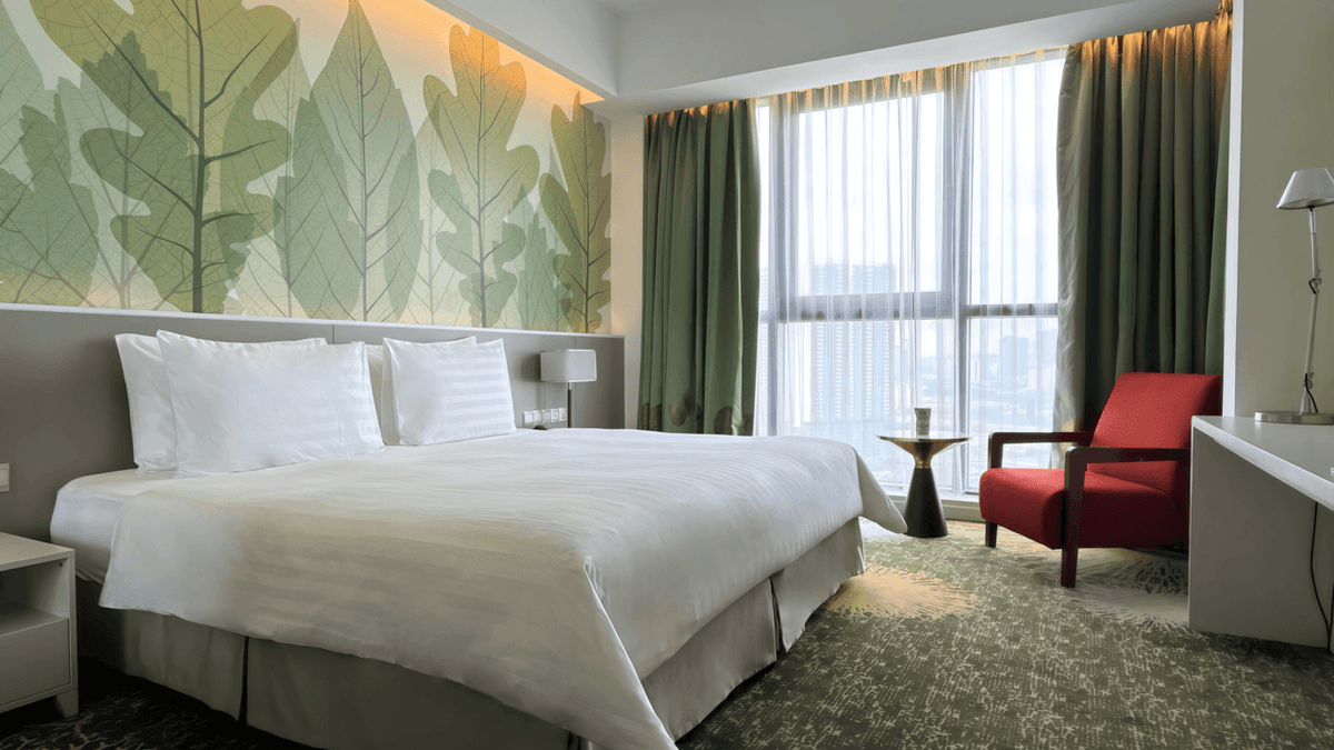 Deluxe Plus King Room with a large bed, chair, and city view at Sunway Velocity Hotel in Kuala Lumpur.