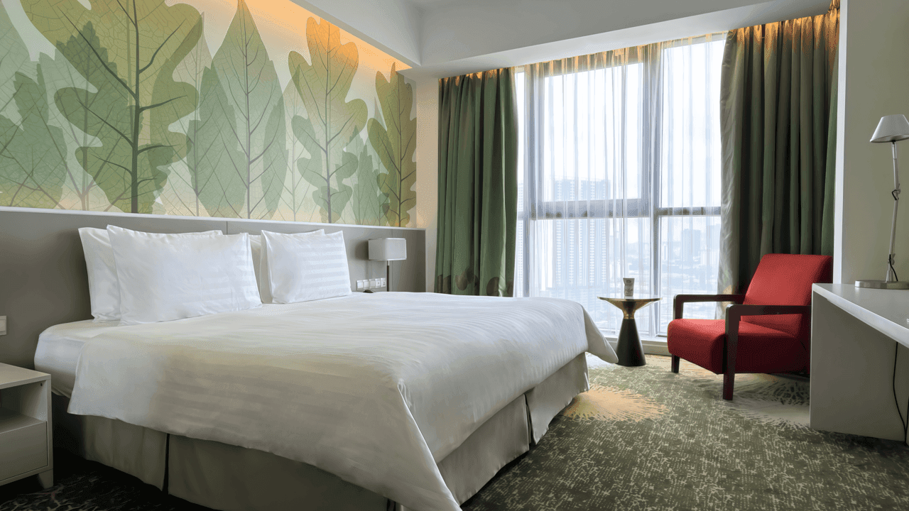 Deluxe Plus King Room with a large bed, chair, and city view at Sunway Velocity Hotel in Kuala Lumpur.
