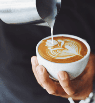 Person pouring milk into a Cappuccino in The Kitchen at Pensativo House Hotel