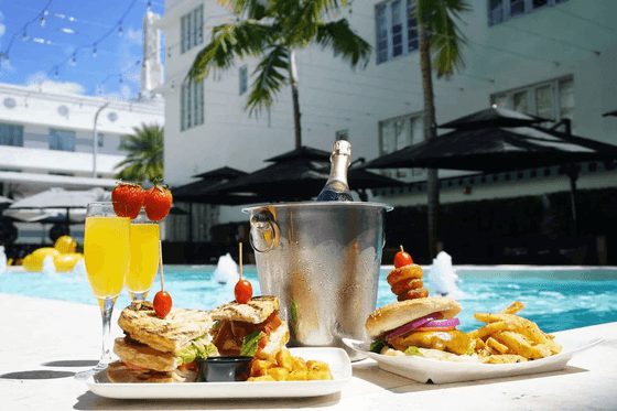 Burgers and fries served with orange juices and a bottle of wine by the pool in Sola Restaurant at Fairwind Hotel Miami