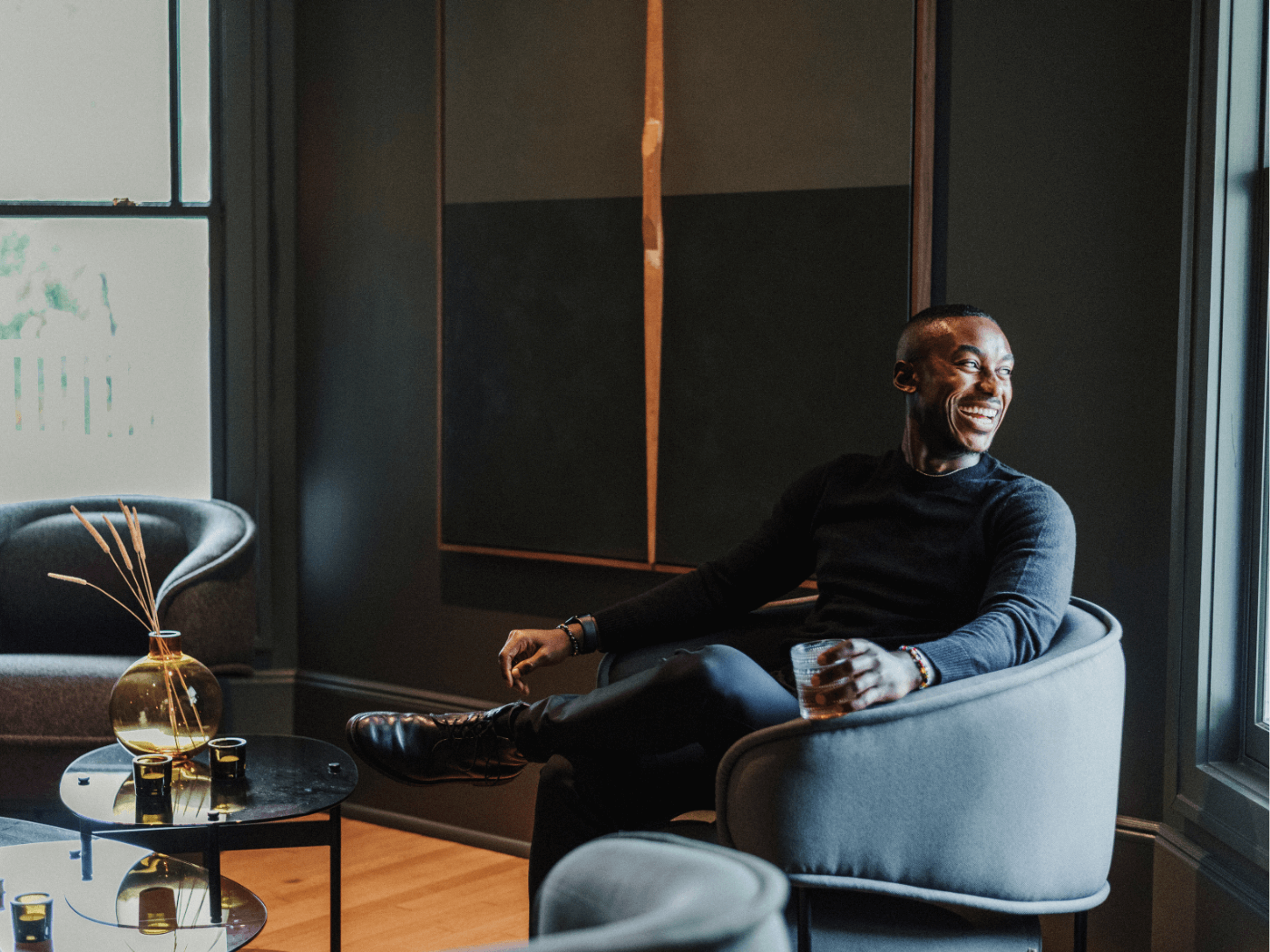 A jovial guest enjoying a glass of whiskey and sitting in the lobby of the hotel