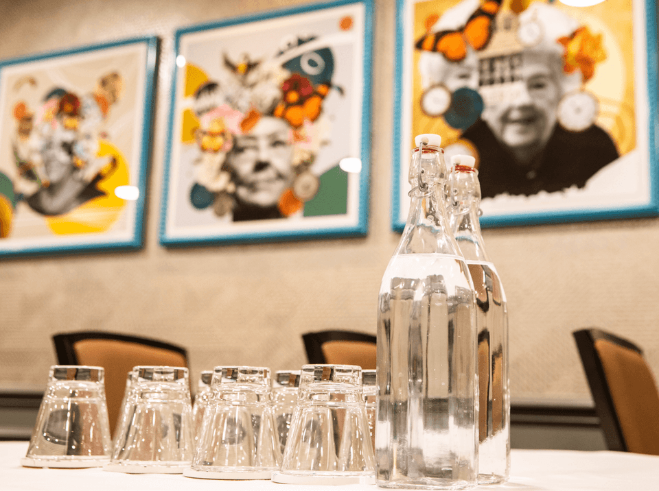Glass water bottles and tumblers arranged in a meeting room at The Met Hotel Leeds, England, under colourful art
