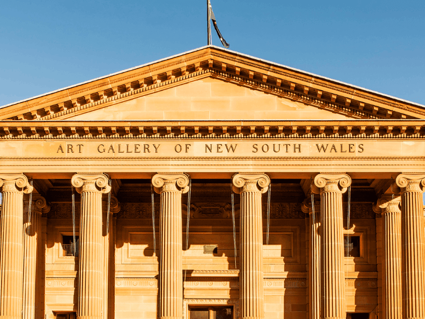 Front facade of Art Gallery of New South Wales with columns and blue sky above.