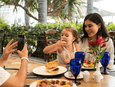 Family dining at Sunset Restaurant with father taking photo of child at Buenaventura Grand Hotel and Spa
