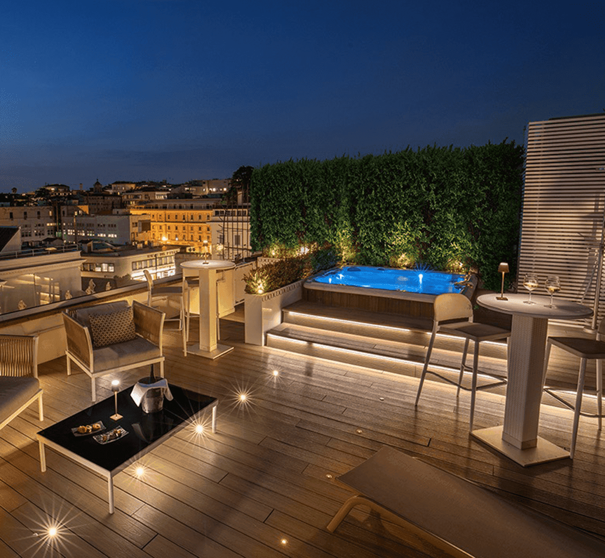 Elegant rooftop terrace at The Glam Hotel with hot tub, cozy seating, soft lighting, and night city views by AG Hotels