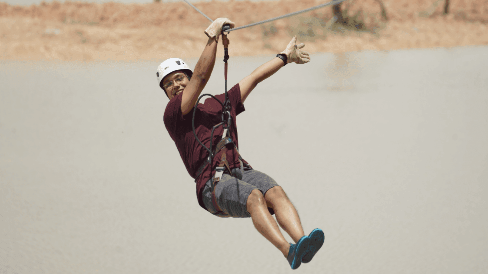 Person in a helmet and gloves zip-lining above a river near Sunway Hotel Big Box