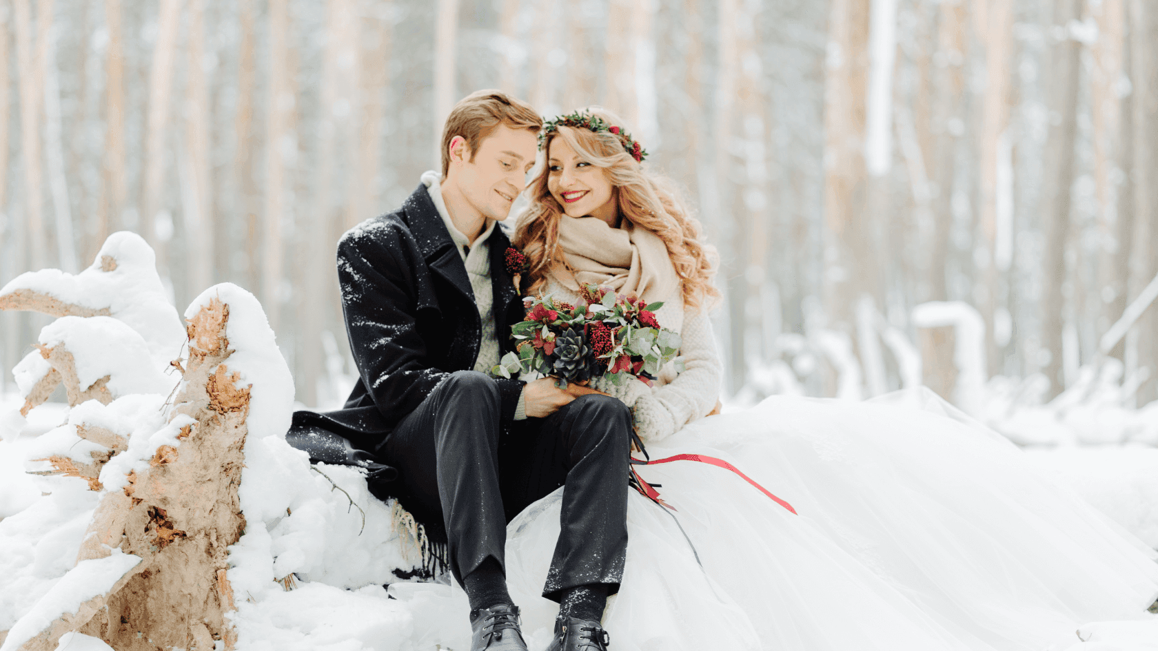 Bride and groom sitting close together on a snow-covered log in the forest, near The Grand Summit Hotel at Attitash